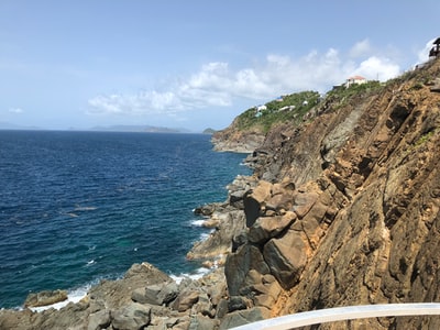 Under the blue sky during the day, brown rocky mountain by the sea
